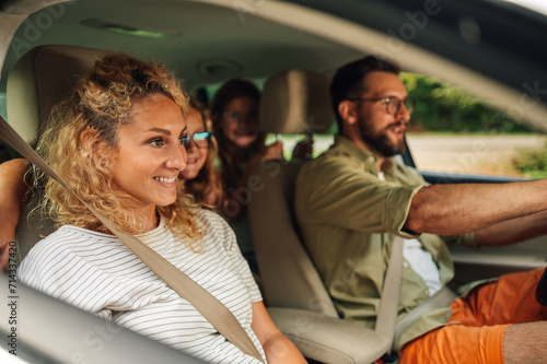 Mother on passenger seat enjoying road trip and traveling by car with her family