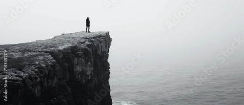 dramatic black and white image of a lone figure standing on a cliff overlooking the sea, reciting poetry to the vast ocean, symbolizing freedom and the power of words photo
