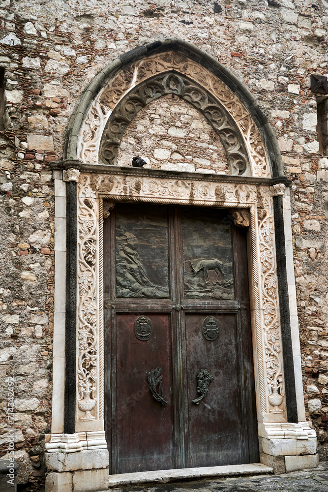 Wooden, decorated door of a medieval stone church in Taormina on the island of Sicily
