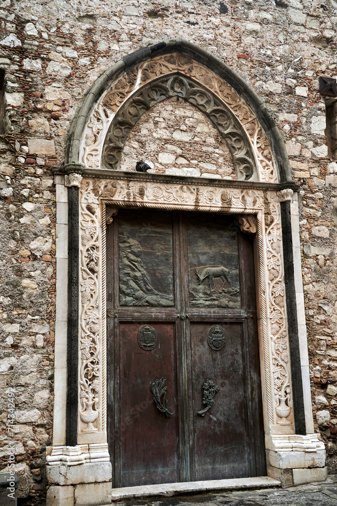 Wooden, decorated door of a medieval stone church in Taormina on the island of Sicily Wooden, decorated door of a medieval stone church in Taormina on the island of Sicily