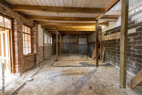 Abandoned building interior in disrepair with debris  exposed pipes  and missing doors awaiting renovation