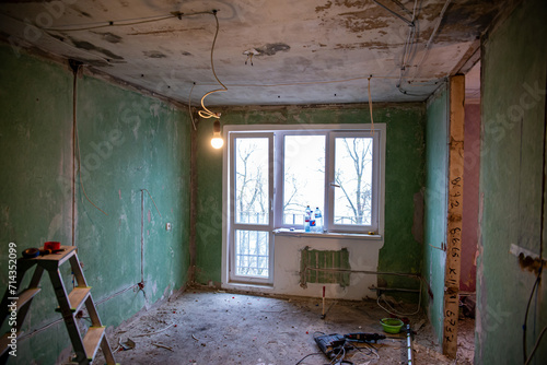 Abandoned building interior in disrepair with debris, exposed pipes, and missing doors awaiting renovation