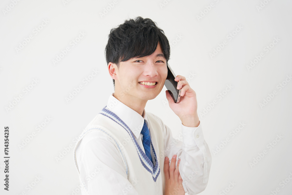 スマートフォンで電話する男子高校生 白背景 カメラ目線 スマートフォンで電話する男子高校生 白背景 カメラ目線