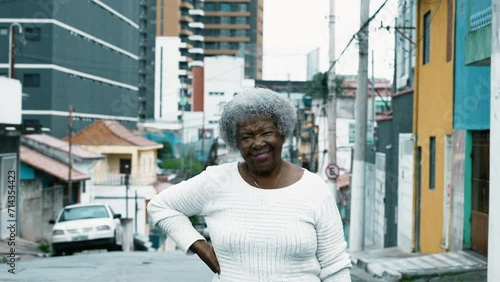 Portrait of a South American older lady standing in urban city street. African American 80s woman posing for camera outside photo