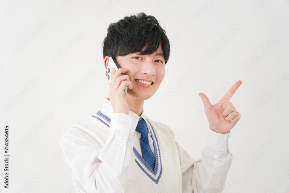 スマートフォンで電話しながらチャックサインをする男子高校生　白背景