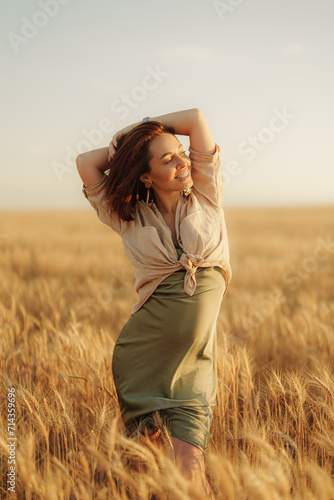 A woman's carefree spirit shines as she embraces herself, surrounded by the rich glow of the wheat field at sunset © arthurhidden