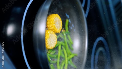 Frying maize and green beans on the frying-pan. Preparing the side dish for the meat course. Vertical screen. Close up. photo