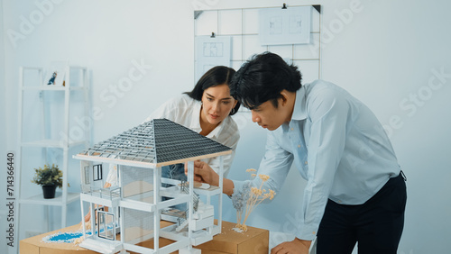 Closeup of young professional skilled architect engineer team focusing on checking the house model structure at modern office. Creative professional design and teamwork concept. Immaculate.