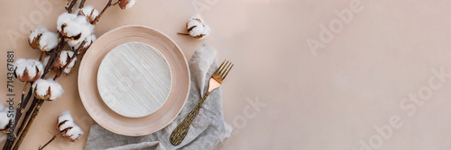 Panorama. Modern minimal table place setting neutral peach fuzz color top view decorated with flowers cotton branch. Space for text or menu. Scandinavian style tableware.