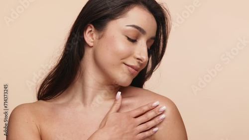 Elegant brunette woman applying cream on her shoulder, depicting beauty and skincare routines. Perfect for wellness and cosmetics themes. photo