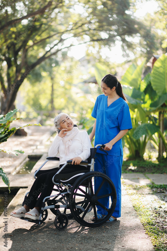 Elderly asian senior woman on wheelchair with Asian careful caregiver and encourage patient, walking in garden. with care from a caregiver. and senior health insurance Elderly asian senior woman on wheelchair with Asian careful caregiver and encourage patient, walking in garden. with care from a caregiver. and senior health insurance