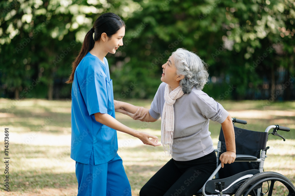 Asian young caregiver nurse support senior older female walking outdoors. Specialis doctor help and take care of elderly mature.
