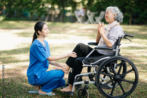 Asian physiotherapist helping elderly woman patient stretching arm during exercise correct with dumbbell in hand during training hand with patient Back problems in the garden. © Nuttapong punna