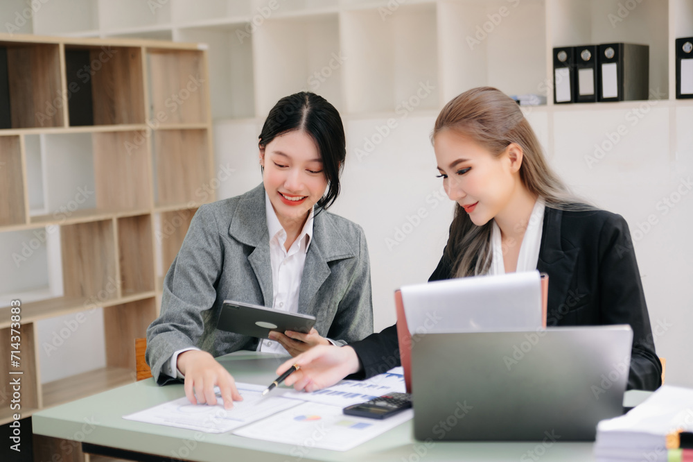 Two Asian businesswoman and man discuss investment project working and planning strategy with tablet laptop computer in office.. Two Asian businesswoman and man discuss investment project working and planning strategy with tablet laptop computer in office..