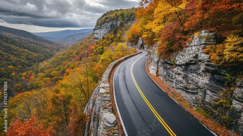  a winding road in the mountains surrounded by trees with orange and yellow foliage on both sides of the road is surrounded by rocks and trees with orange and yellow leaves on both sides.
