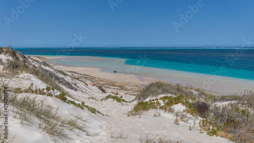 People walking on white sand of Paradise Beach with turquoise water behind - Coral Bay, Ningaloo Reef, Western Australia 