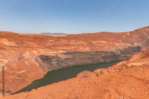 Massive open cut iron ore mine with water in the bottom - Mount Tom Price, Western Australia