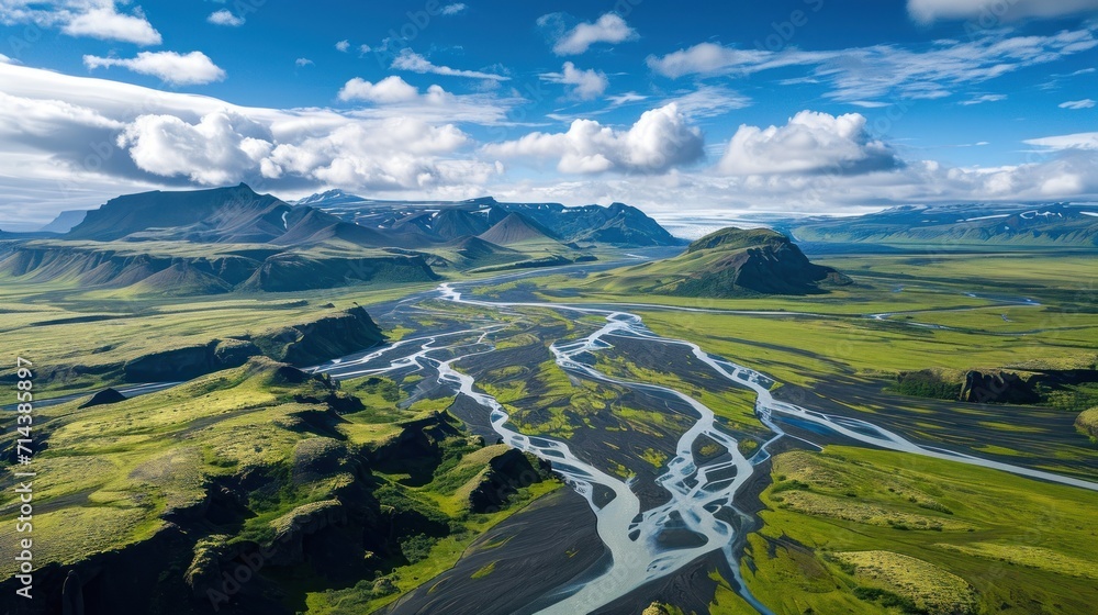  an aerial view of a river running through a valley with mountains in the background and a blue sky with white clouds in the middle of the photo, and a river running through the center.