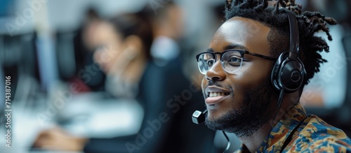 A black man in a telemarketing office speaks to a customer service consultant on the phone, providing support and advice in online finance through a CRM system.