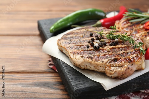Delicious grilled pork steaks with spices on wooden table, closeup. Space for text