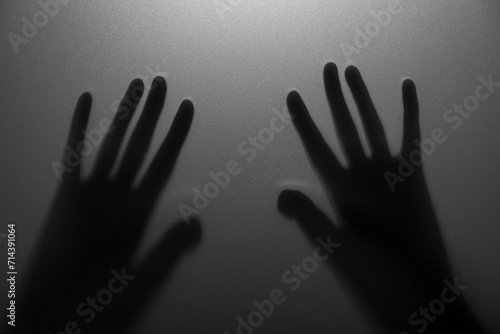 Silhouette of creepy ghost behind glass against grey background, closeup