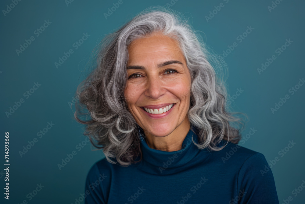 A woman with gray hair is smiling and wearing a blue turtleneck A woman with gray hair is smiling and wearing a blue turtleneck