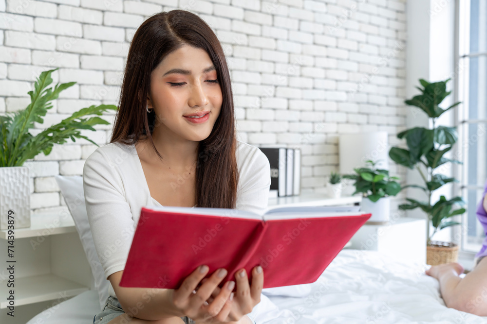 Young woman reading novel while relaxing in bed at home, portrait of female enjoying book in bedroom Young woman reading novel while relaxing in bed at home, portrait of female enjoying book in bedroom