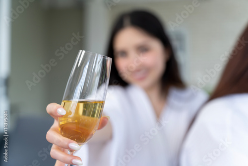 Young lady in white robe holding up wineglass indoors, concept image for event