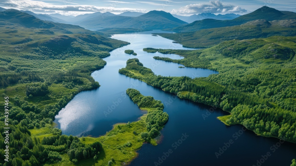  an aerial view of a body of water surrounded by lush green hills and a blue sky with a few clouds in the top of the picture and a few trees in the foreground.