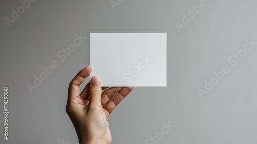  a hand holding a white card isolated on grey background, generative ai