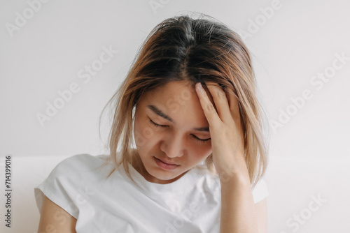 Close up headshot of headache hangover Asian woman with hand covering her head.