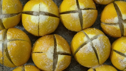 Preparing preserved lemons. Top view of cross-cut lemons sprinkled with non-iodized salt on a plate. photo