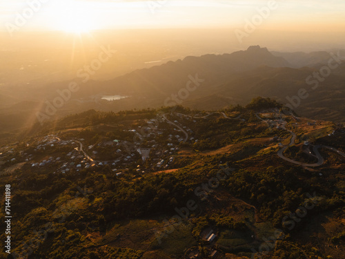 The golden sunset sky bathes a secluded mountain village and its winding roads in a warm, inviting light, showcasing the tranquil rural beauty. © Touchr