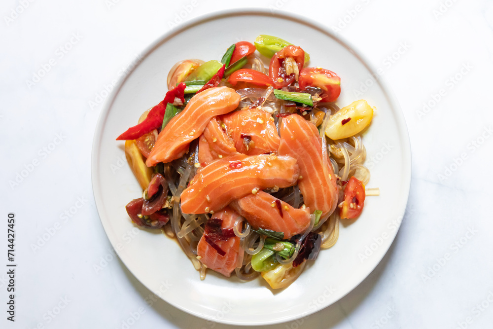 Spicy salad with fresh salmon and potato noodles mixed fermented fish sauce on white plate. Spicy salad with fresh salmon and potato noodles mixed fermented fish sauce on white plate.