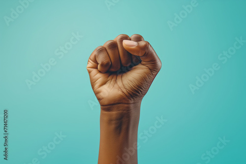 Raised clenched fist symbolizing female power and black women's equality on a teal background, suitable for Black History Month and Women's Day. photo