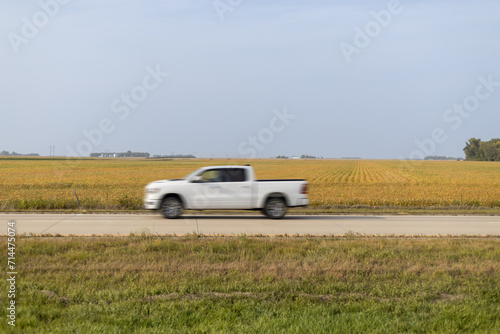White Pickup Truck Speeding Along Rural Road by Golden Fields