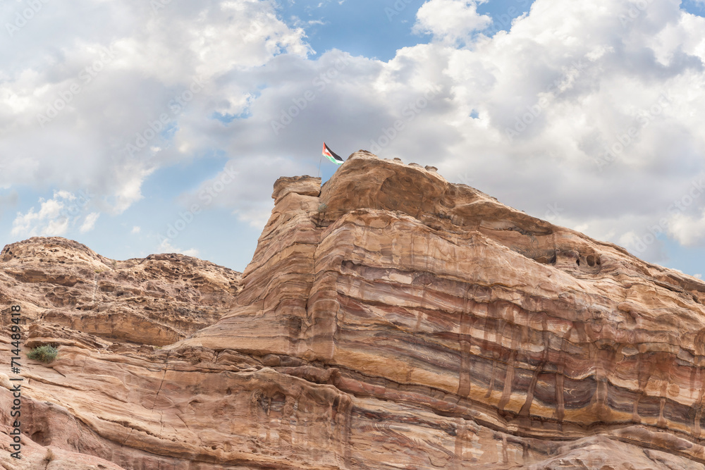 The Jordanian national flag flutters in the wind on top of a cliff in Nabatean Kingdom of Petra in Wadi Musa city in Jordan