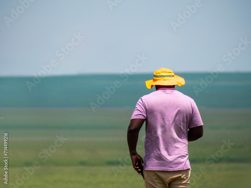 Travailleur vu de dos en train de marcher en direction d'un terrain agricole © Romane