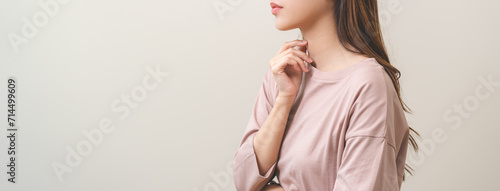 Sickness in inflaming asian young woman, girl use hand check self touch at sore throat, pain thyroid gland on neck or disease reflux, acid of suffer people on wall background. Medical and healthcare. photo