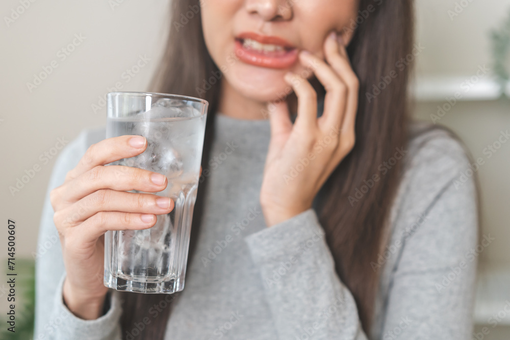 Suffering from toothache, hurt asian young woman touch cheek, face expression ache or feel pain, sensitive molar teeth, hand holding glass of water with ice, inflammation when drink cold, healthcare. Suffering from toothache, hurt asian young woman touch cheek, face expression ache or feel pain, sensitive molar teeth, hand holding glass of water with ice, inflammation when drink cold, healthcare.