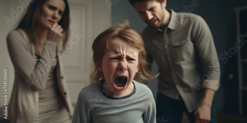 A young child crying loudly in distress with anxious parents trying to soothe and calm them down in a home setting. photo