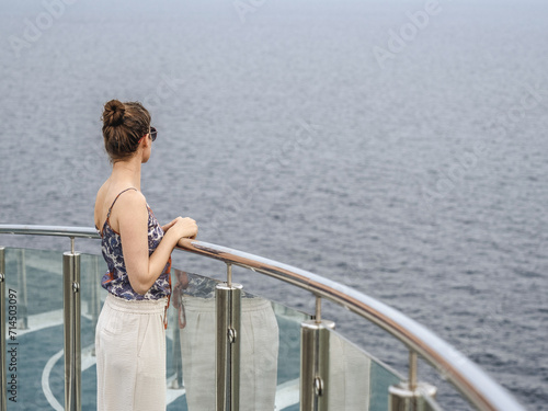 Cute woman standing on the empty deck of a cruise liner against the backdrop of sea waves. Sunny, clear day. Closeup, outdoor. Vacation and travel concept © Svetlana