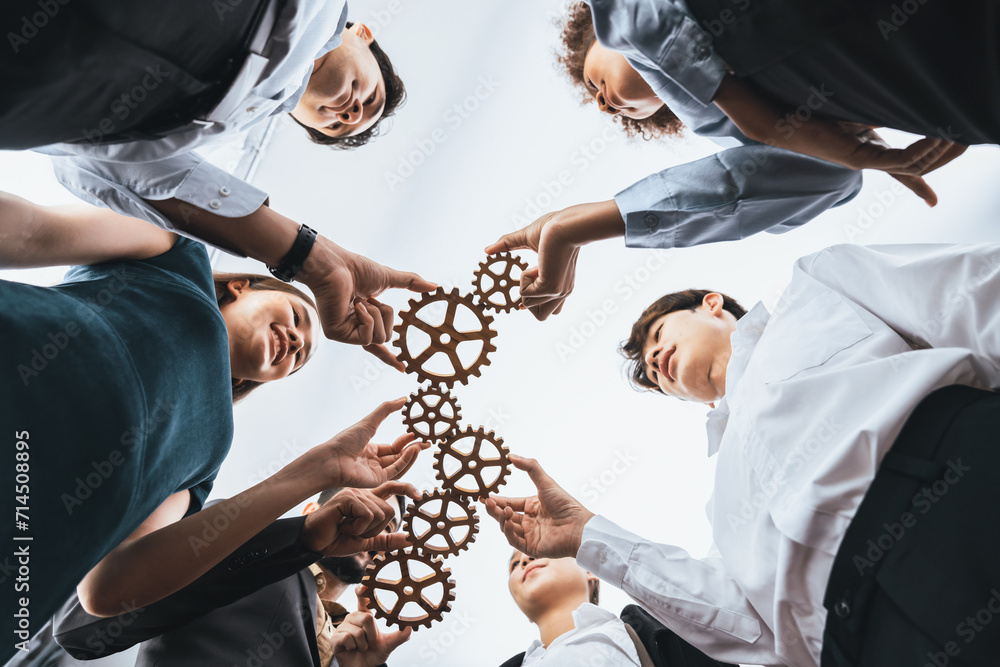 Below view office worker holding cog wheel as unity and teamwork in