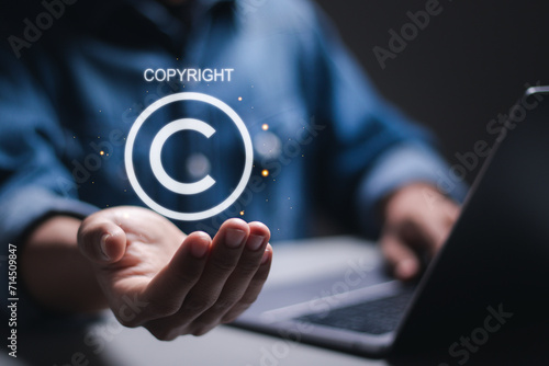 Copyright or patent concept. Person use laptop with virtual copyright symbol for author rights and patented intellectual property. photo
