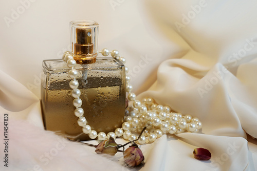 Blank perfume bottle with gold and marble cup in front of a brunch of cherry blossom. Photography in beige tones