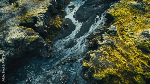  an aerial view of a stream running through a rocky area with green moss growing on the rocks and the water flowing down the side of the stream in between the rocks.