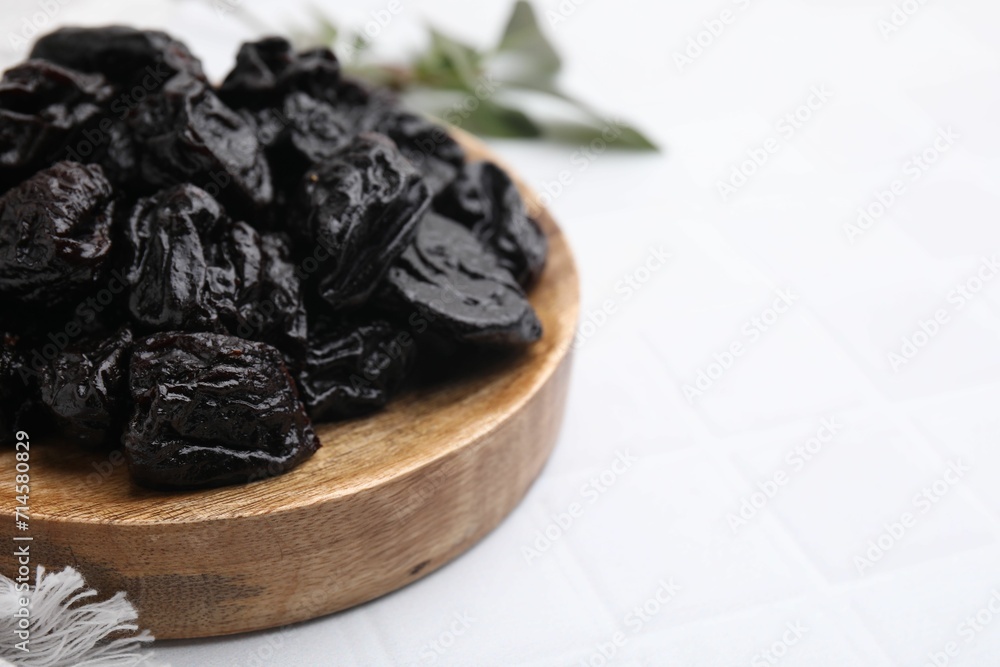 Sweet dried prunes on white tiled table, closeup. Space for text Sweet dried prunes on white tiled table, closeup. Space for text