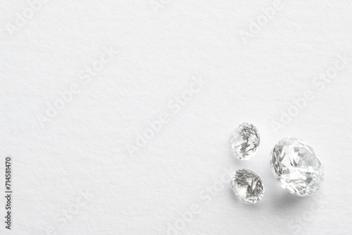 Beautiful shiny diamonds on white background, flat lay. Space for text