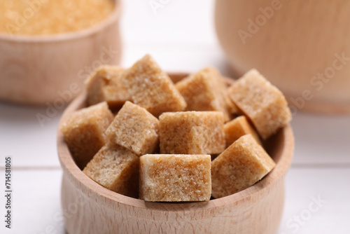 Brown sugar cubes in bowl on table, closeup