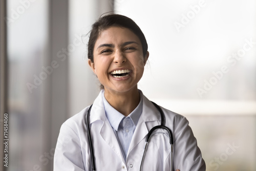 Cheerful Indian doctor woman in uniform with stethoscope looking at camera, laughing out loud, posing for head shot portrait, having fun, enjoying medical profession, successful career in medicine photo